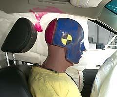 The frontal airbag and both side airbags inflated for the driver dummy. Smeared greasepaint indicates where the dummy's head hit the side curtain airbag, its fabric cover, and the head restraint during rebound