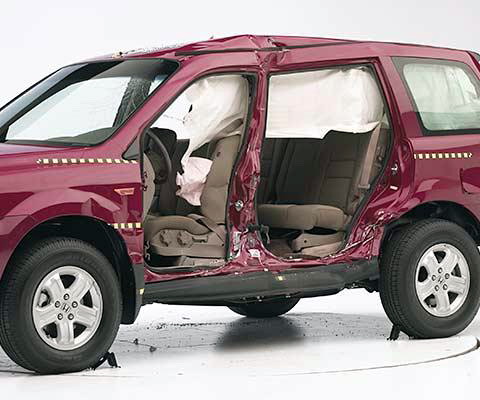 View of the vehicle after the crash with doors removed, showing the side airbags and damage to the occupant compartment