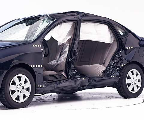 View of the vehicle after the crash with doors removed, showing the side airbags and damage to the occupant compartment