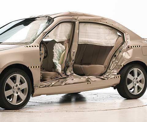 View of the vehicle after the crash with doors removed, showing the side airbags and damage to the occupant compartment