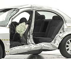 View of the vehicle after the crash with doors removed, showing the side airbag and damage to the occupant compartment
