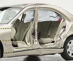 View of the vehicle after the crash with doors removed, showing the side curtain airbag and damage to the occupant compartment