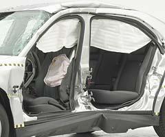 View of the vehicle after the crash with doors removed, showing the side airbags and damage to the occupant compartment.