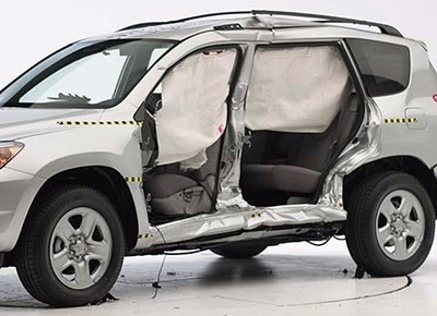 View of the vehicle after the crash with doors removed, showing the side airbags and damage to the occupant compartment