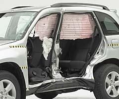 View of the vehicle after the crash with doors removed, showing the side airbags and damage to the occupant compartment