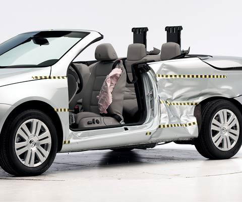 View of the vehicle after the crash with door removed, showing the side airbag, pop-up rollover bars, and damage to the occupant compartment